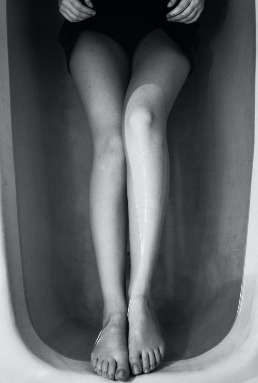 Woman soaking in a bathtub. All we see are her legs.
